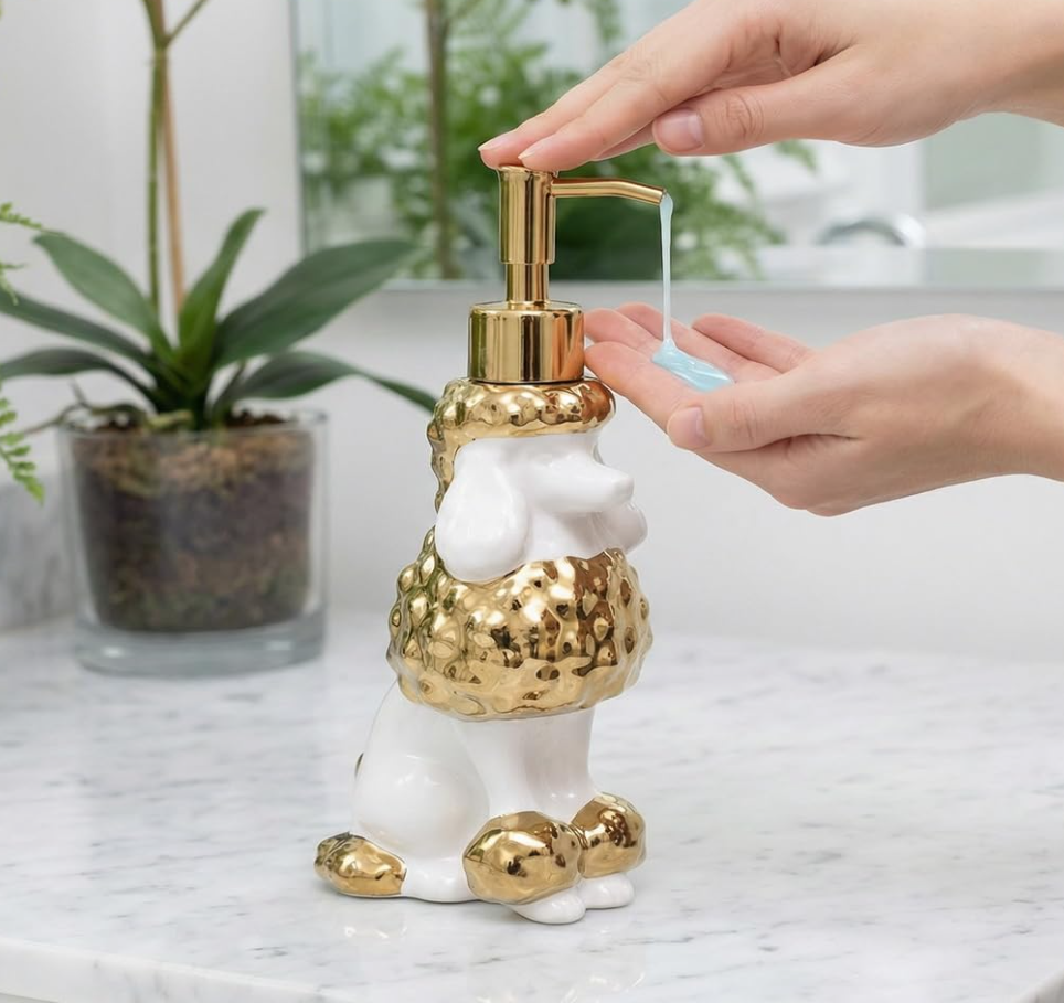 White and gold Newhengs poodle soap dispenser in use beside a bathroom sink